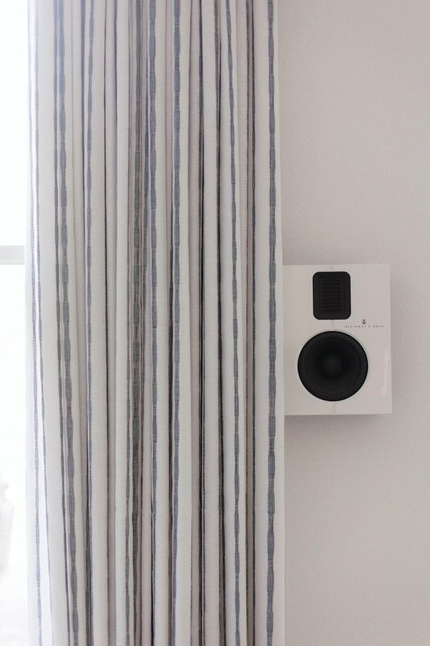 Steinway & Sons Speaker on a white wall beside a white and blue curtain