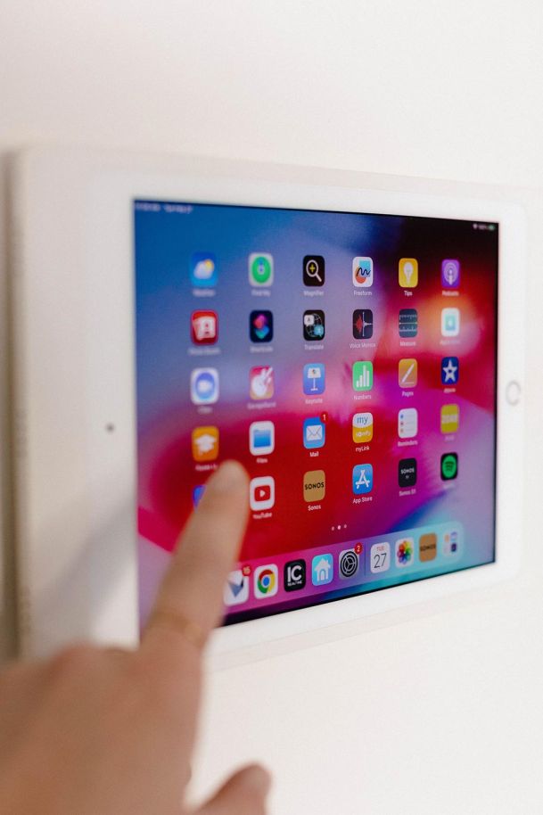 Woman's hand touching an iPad screen installed on a white wall